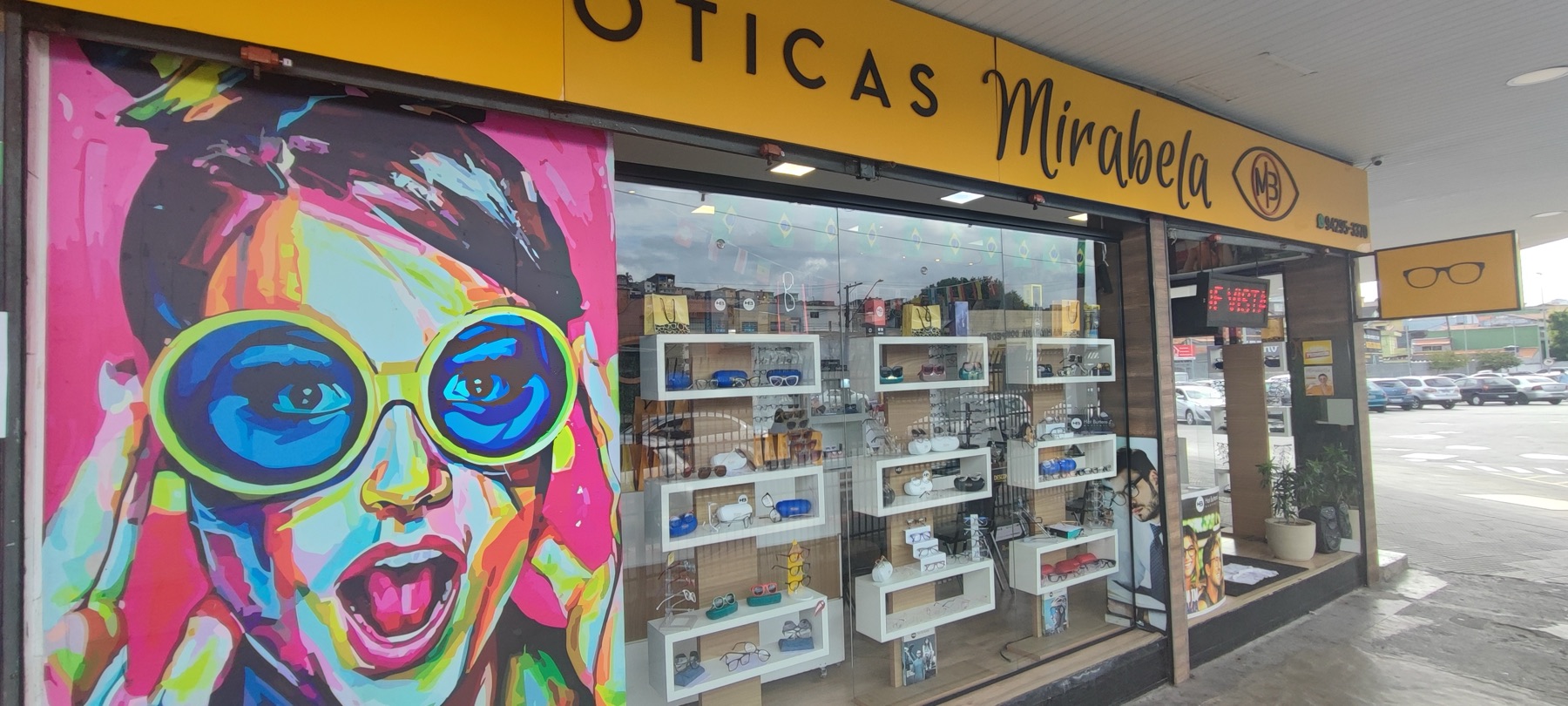 Fachada das Óticas Mirabela, com a placa amarela e o mural colorido, em Santo André